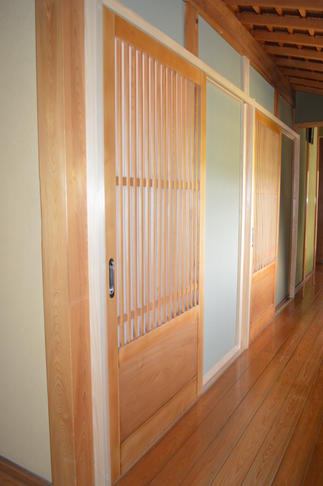 趣きを添えるトイレ入口の建具２本は、以前玄関引戸として使われていました。洗浄して再塗装、職人の技が伺える格子が見事な建具です。