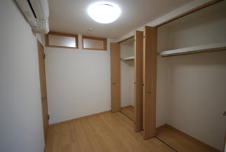 壁一面のクローゼットと、隣との空間をつなぐランマ窓を配置した寝室