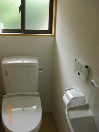掃除道具も収納できる手洗い器が備え付けられた、明るいトイレ。