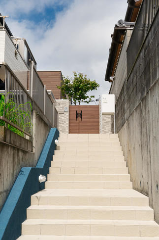 階段脇の青い壁にマリンランプ。門に続く白い階段と宅配ボックスが爽やかです。