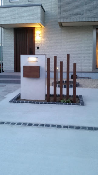 玄関ドアのイメージに合った門柱やアプローチ。日が暮れると明かりが灯り更に雰囲気が素敵です。