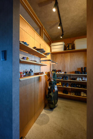 木目の壁と棚で統一された、温かみのあるシューズクローク