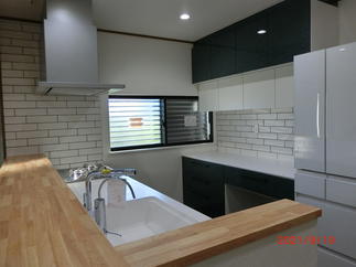 グリーンの収納扉にアクセントタイルが生えるキッチン