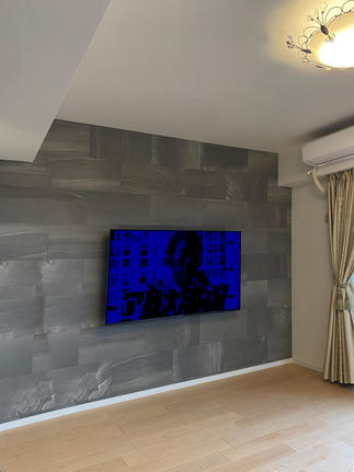 リビングの壁掛けテレビ後方には「エコカラット：ストーングレース」のダークグレーを採用